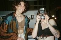 two women standing next to each other holding a camera