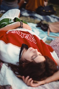 a woman laying on a blanket with a cell phone